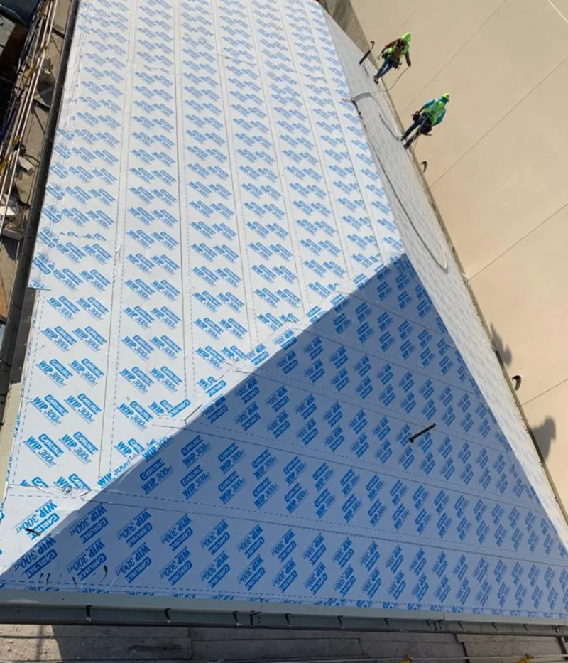 Professional roofers installing underlayment on a metal roof in Wall